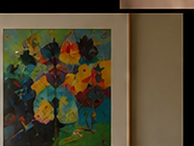 A vividly colored framed painting hanging above a walnut console table.