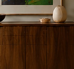 A turned wooden bowl and ceramic vessel resting on a walnut console top.