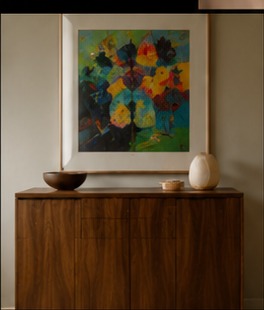 A walnut console table beneath a colorful framed painting, styled with a bowl and ceramic vessel.